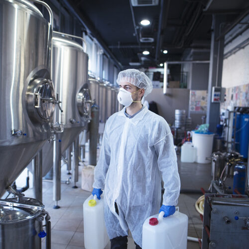 Technologist industrial worker holding plastic canisters about to change chemicals in the food processing machine. Cleaning in food factory.